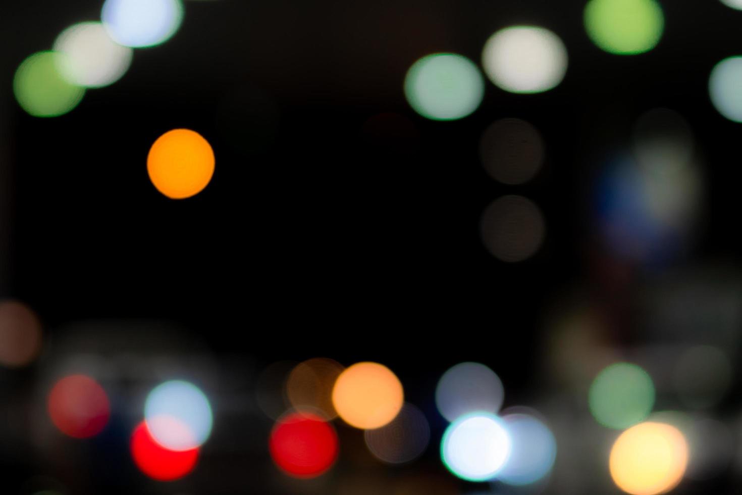 suddig blå, orange, grön, röd och vit bokeh abstrakt bakgrund. oskärpa bokeh på mörk bakgrund. stadsljus på natten. jul eller xmas bakgrund. gatubelysningseffekt med vackert mönster foto