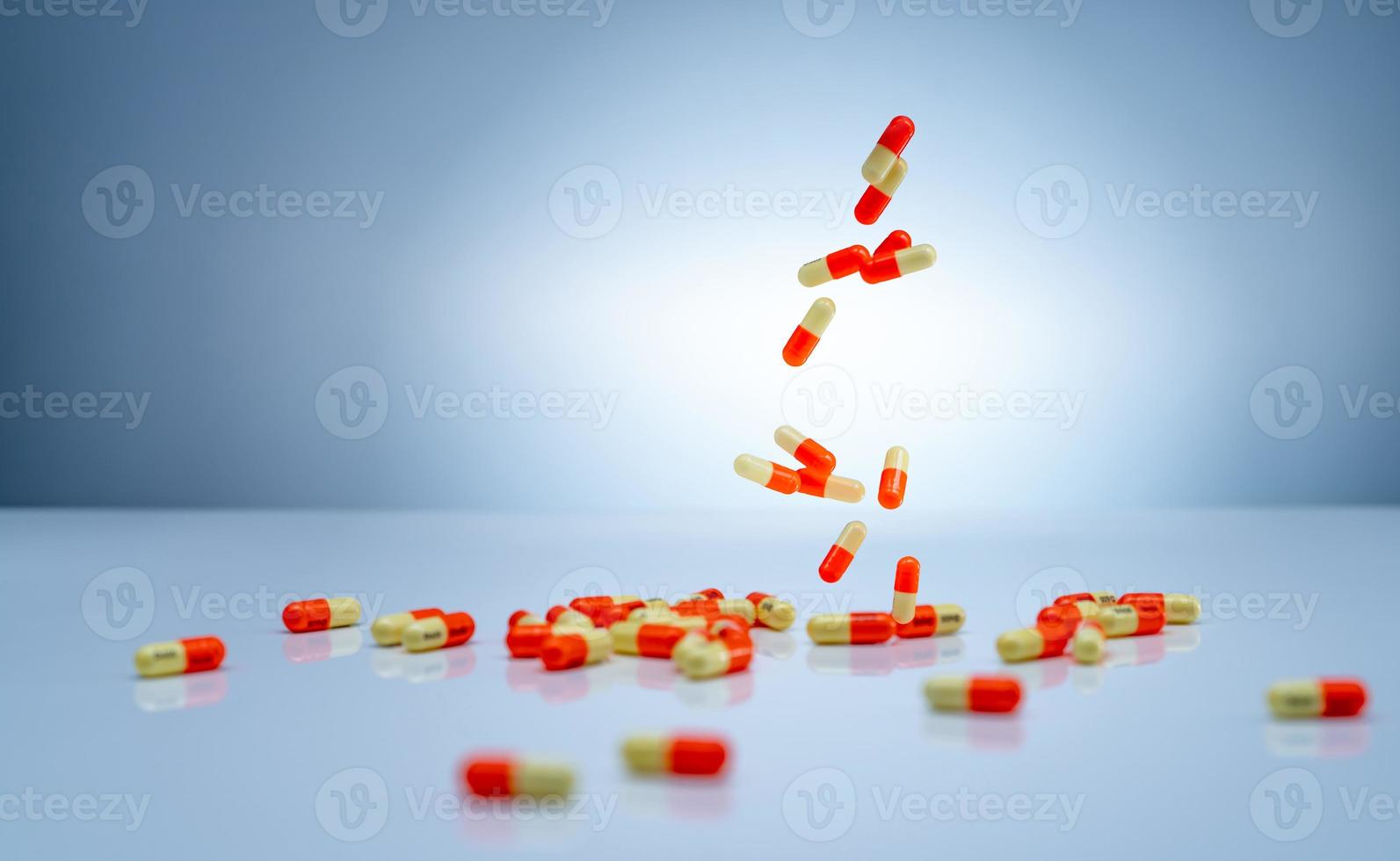 gul orange kapslar piller faller ner på vitt bord. läkemedelsindustri. tranexamsyra kapselpiller för behandling av kraftiga menstruationsblödningar menorragi. läkemedelstillverkning. foto