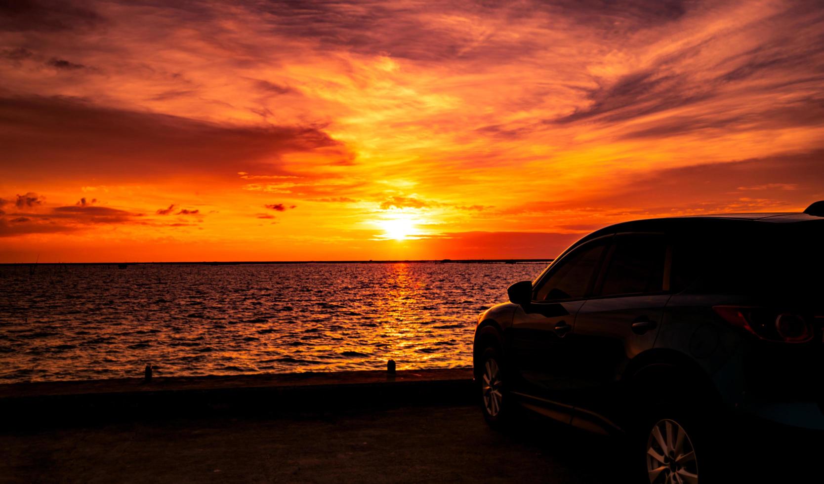 blå kompakt suv-bil med sport- och lyxdesign parkerad på betongväg vid havet i solnedgången. elbilsteknik och affärer. hybridbilar och bilar. tropiska roadtrip-resor. bil- foto