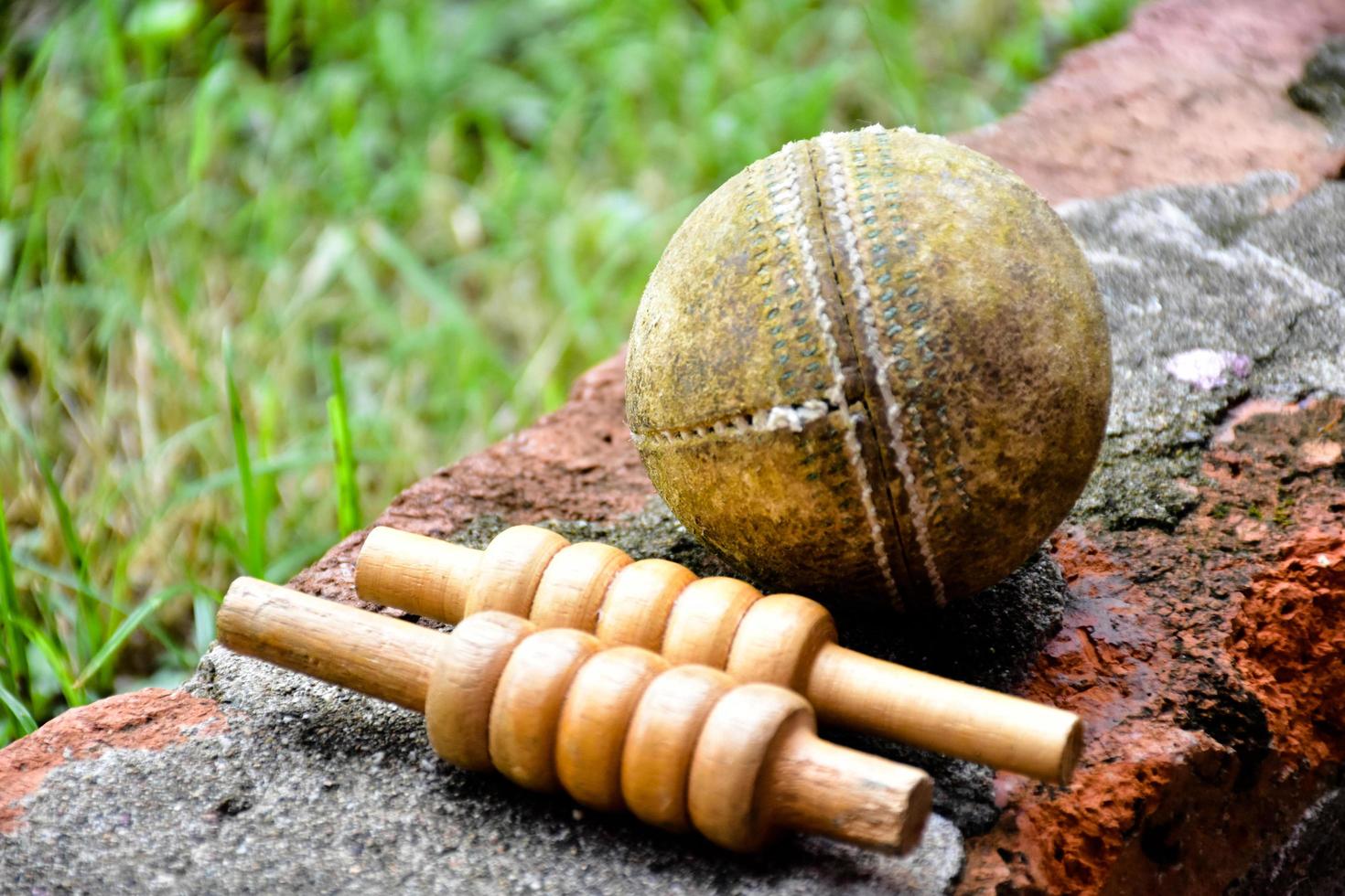 gammal träningsutrustning för cricketsport på mörkt golv, läderboll, wickets, hjälm och träslagträ, mjukt och selektivt fokus, koncept för traditionella cricketsportälskare runt om i världen. foto