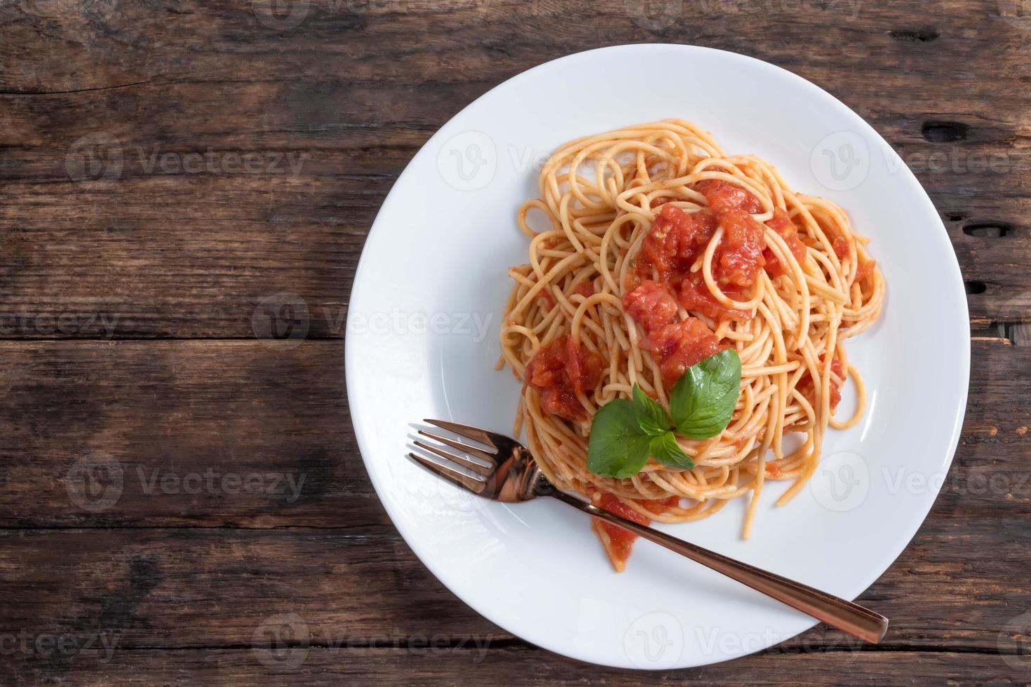 pasta med tomatsås i vit skål på trä bakgrund foto