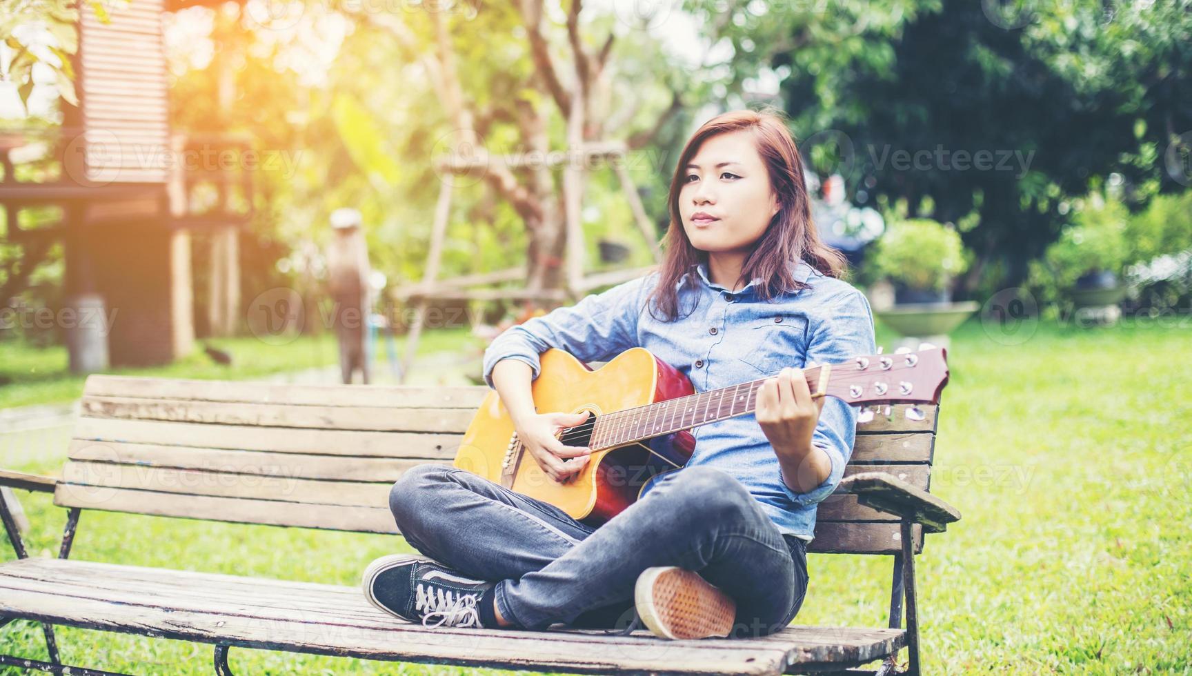 vacker ung kvinna spelar gitarr sitter på bänken, lycklig tid koncept. foto