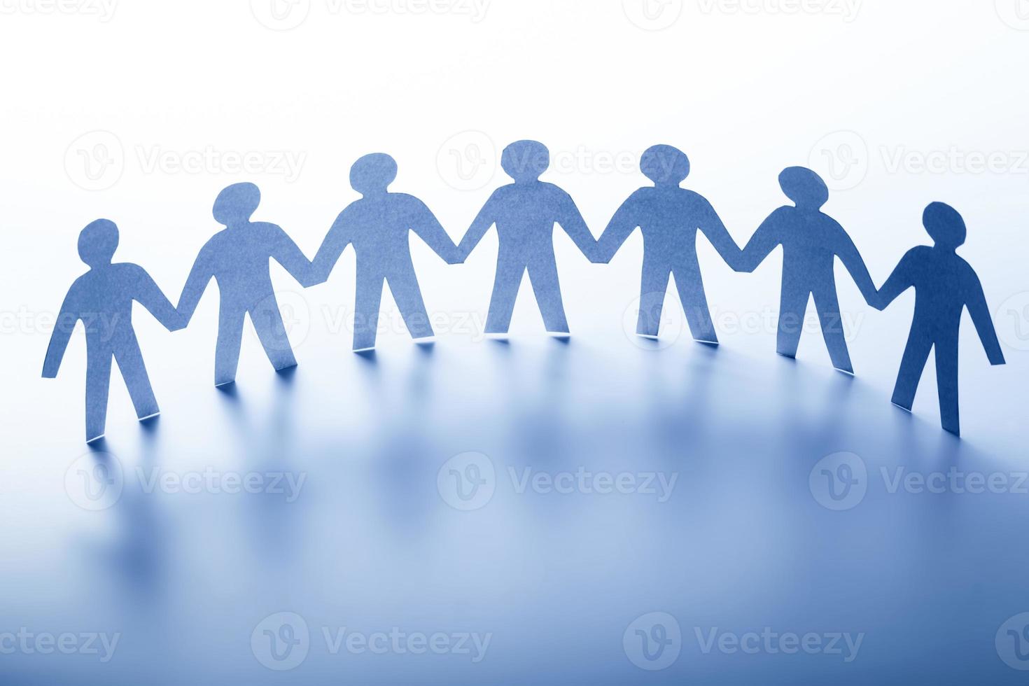 pappersmänniskor som står tillsammans hand i hand. team, samhälle, affärsidé foto