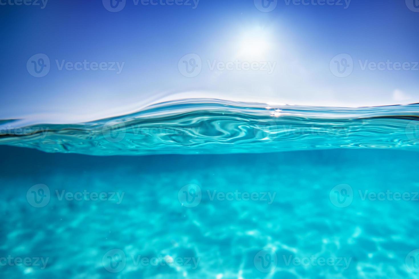 halvt undervattensskott, klart vatten och solig blå himmel. tropiska havet foto