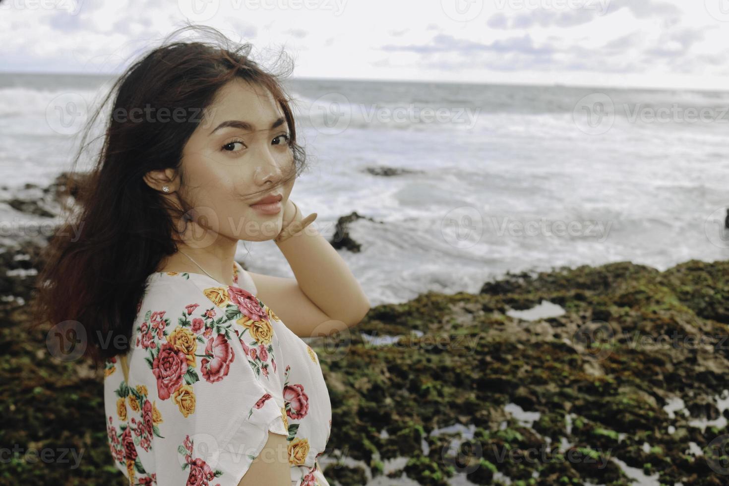 en ung asiatisk flicka på stranden ler mot kameran i gunungkidul, indonesien foto