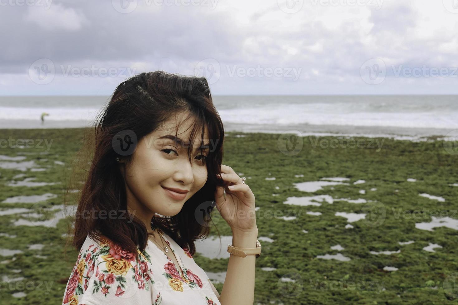 en ung asiatisk flicka på stranden ler mot kameran i gunungkidul, indonesien foto