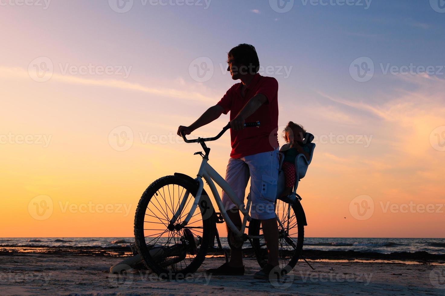 silhuett av far och baby cykling vid solnedgången foto