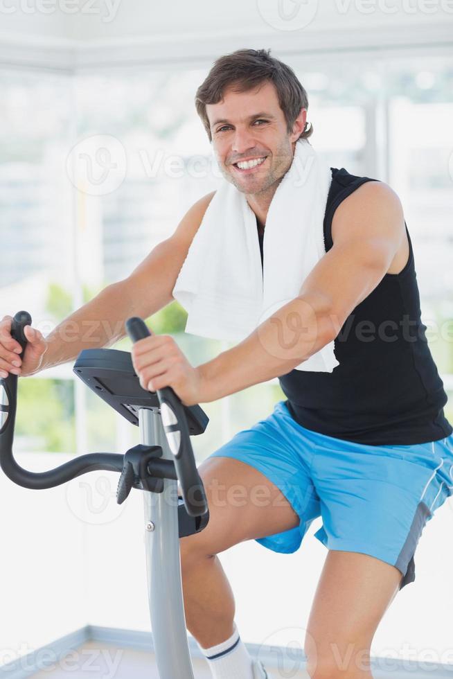 leende man tränar på snurrklassen i ljusa gym foto