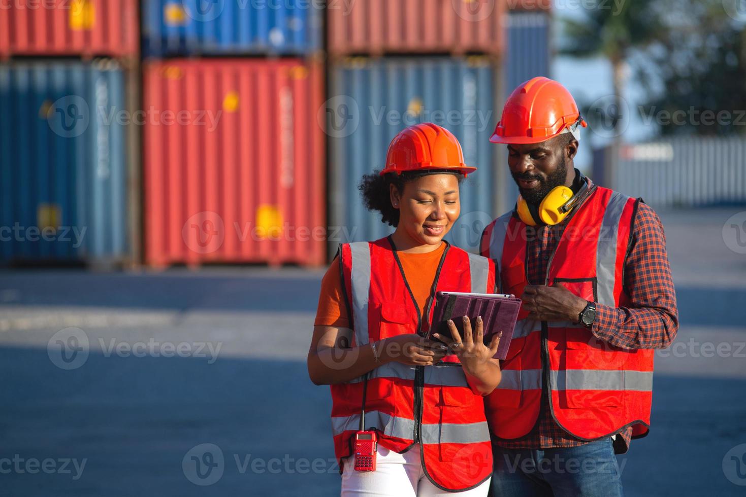 glad afrikansk amerikansk kvinnlig och manlig arbetare som använder surfplatta under videosamtal i en logistisk fraktcontainergård. foto