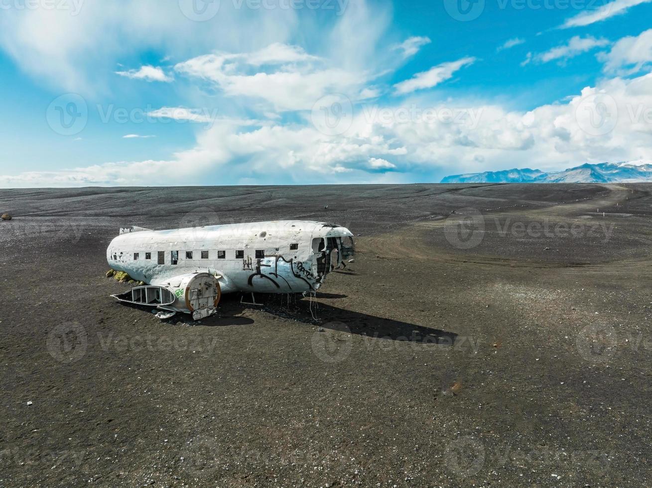 Flygfoto av det gamla kraschade planet övergivet på solheimasandur strand nära vik, island. foto