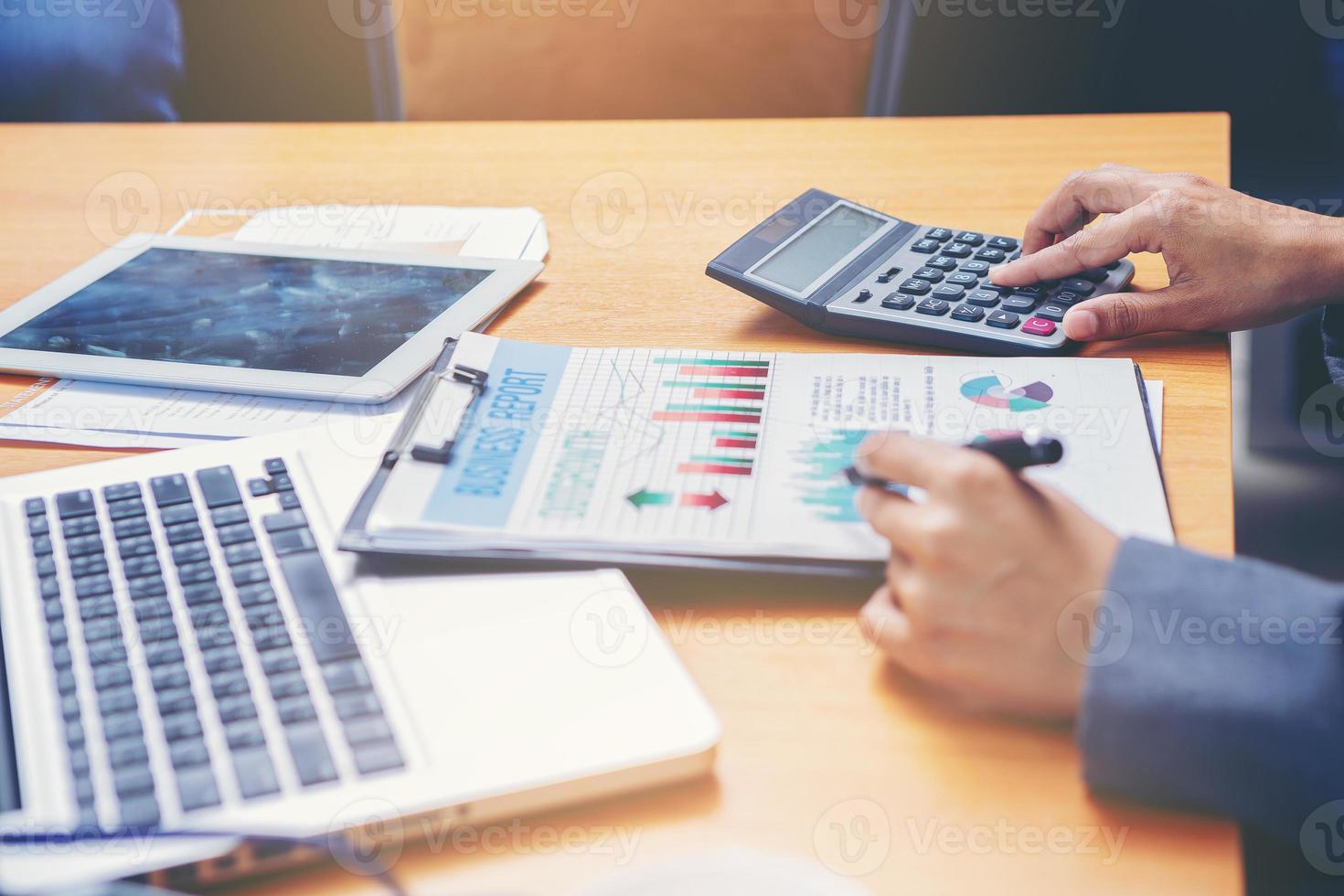 kvinna revisor som arbetar på skrivbordet med hjälp av kalkylator för att beräkna och kontrollera finansrapport. valt fokus foto