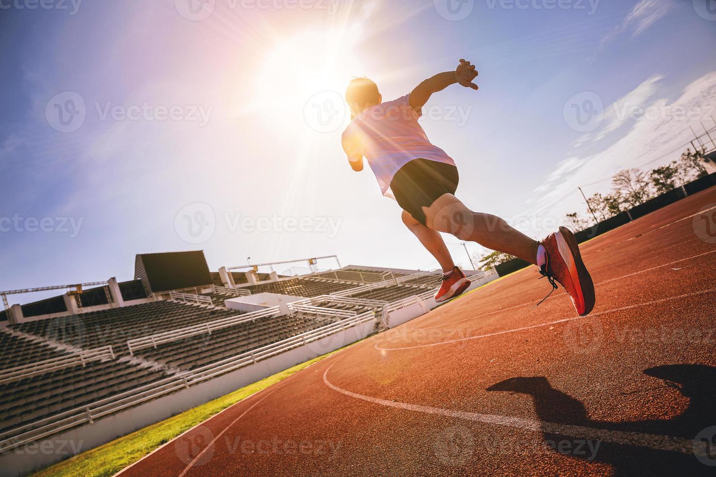 vältränad ung man kör sprint på racerbanan. fit runner fitness runner under utomhusträning på racerbanan. börja springa koncept. foto