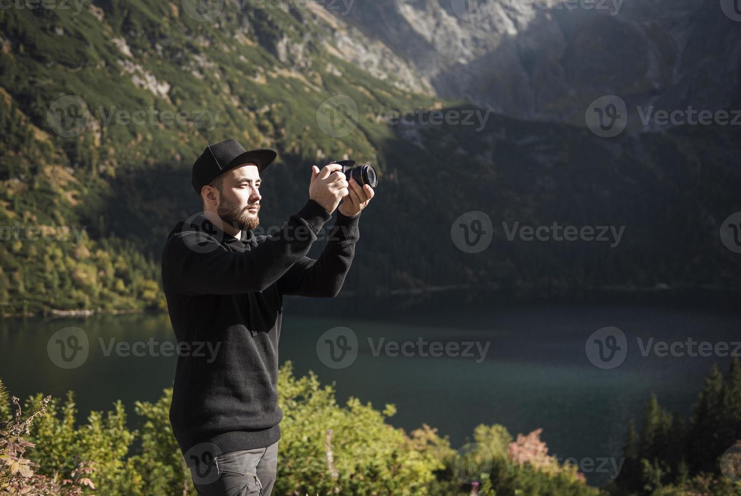 ung man fotograf tar fotografier med digitalkamera i ett berg. foto