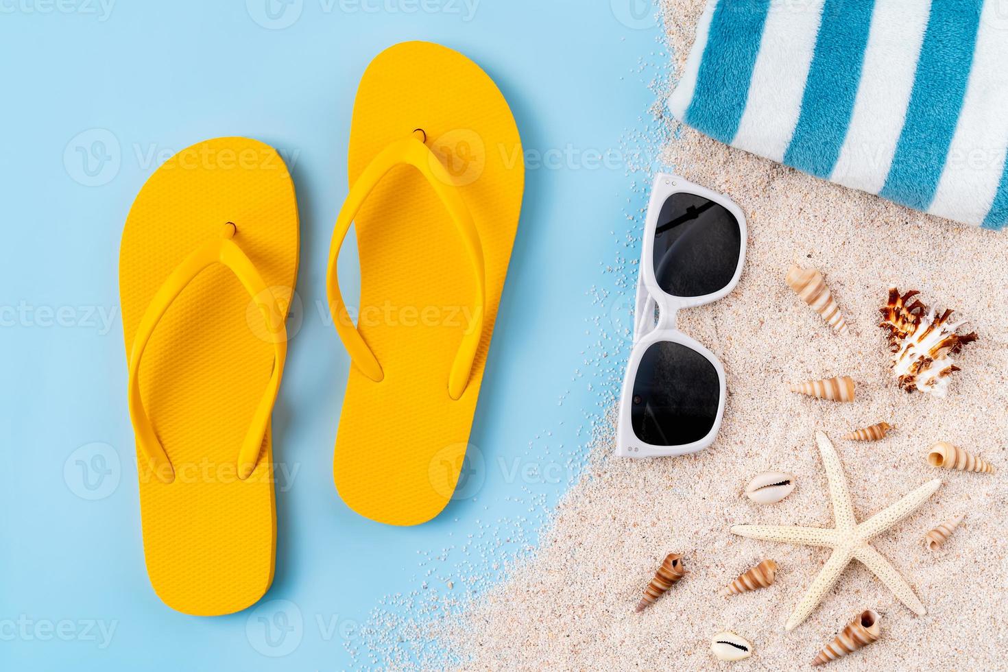 ovanifrån med kopia utrymme av gula sandaler med sjöstjärnor och snäckor, sand på blå bakgrund. foto