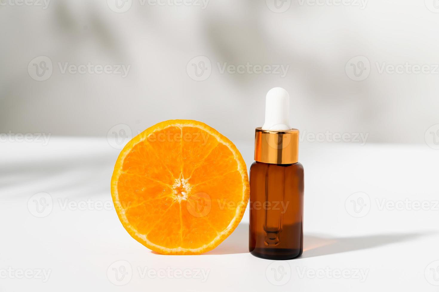 serumflaska med dropper och skiva apelsin, ingredienser för hudvård och behandling vitamin på vit bakgrund, naturlig kosmetika koncept. foto