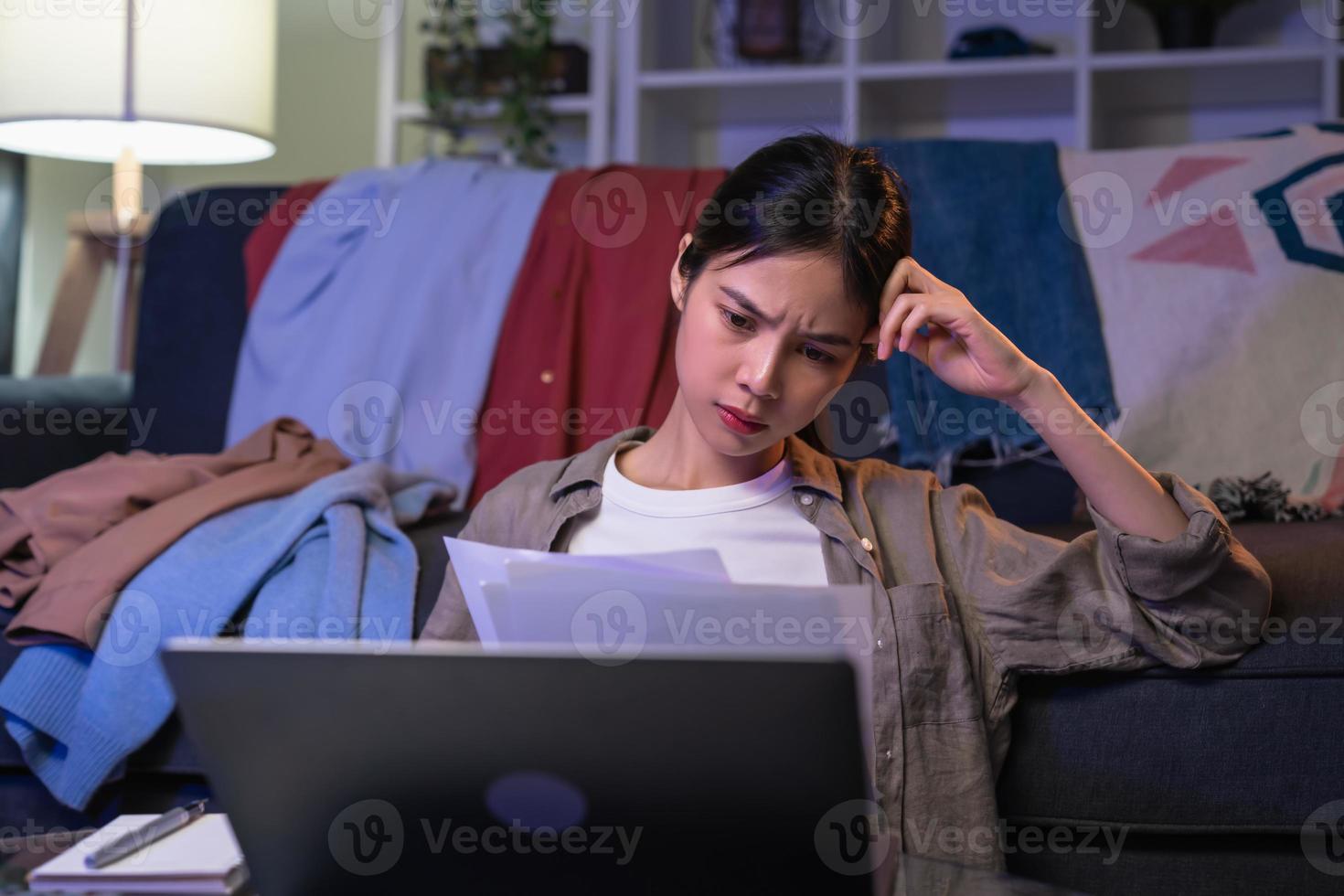 olycklig ung asiatisk kvinna hand som håller utgiftsräkning och beräkning av skuldräkningar varje månad hemma. foto