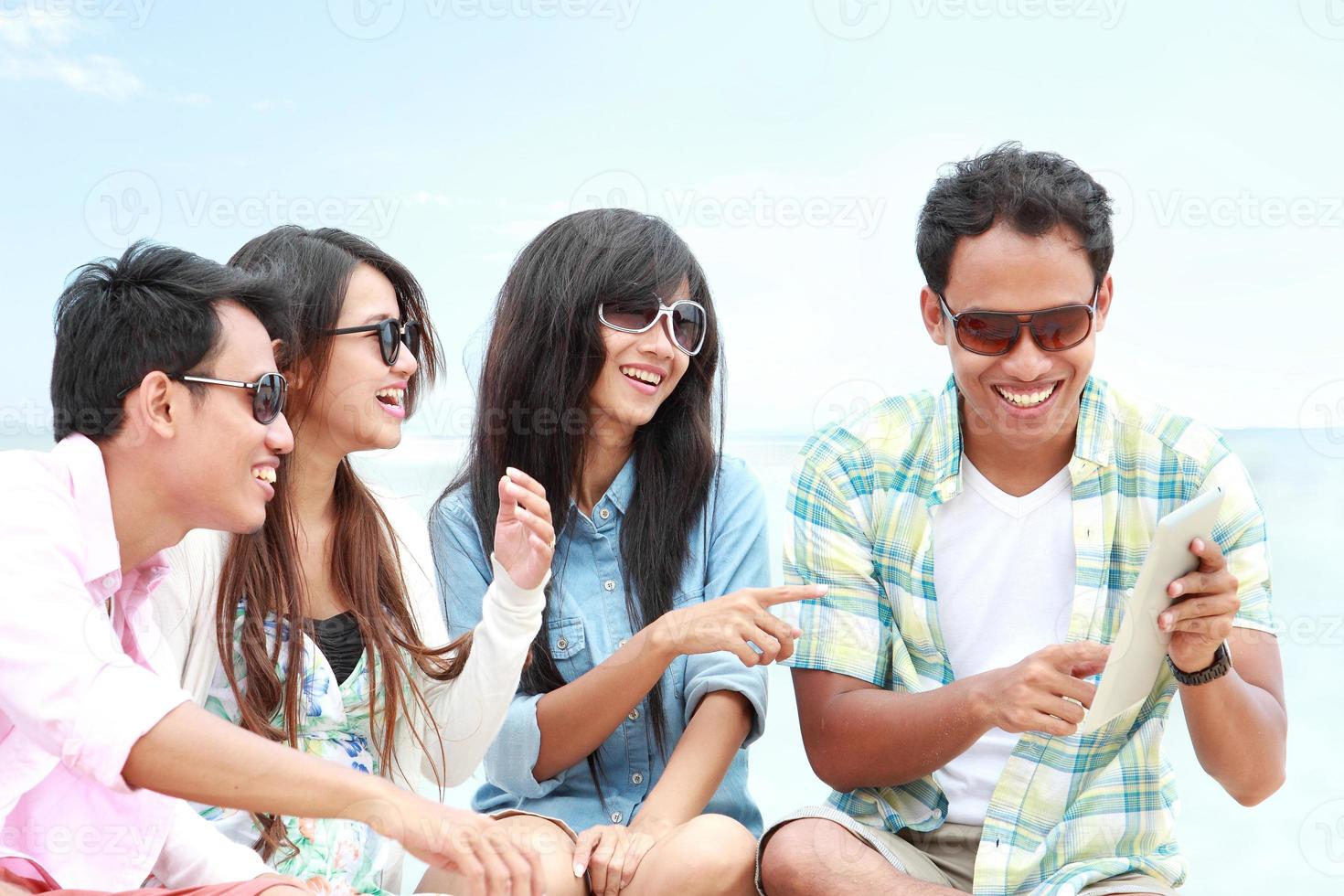 gruppvänner njuter av strandsemester tillsammans med surfplattan foto