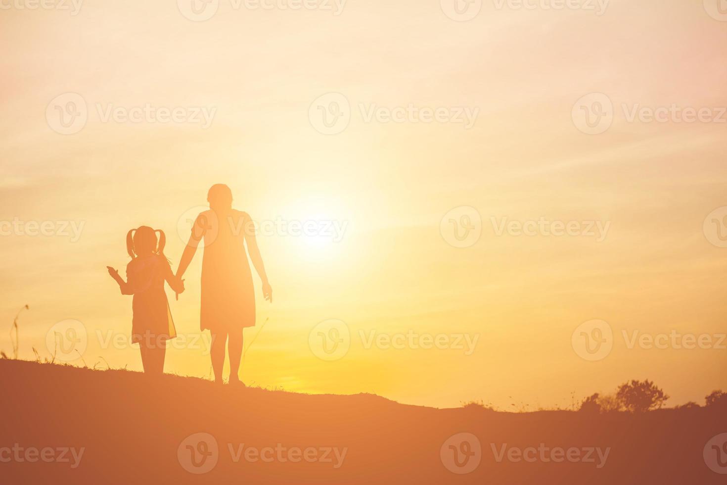 mamma uppmuntrade sin dotter ut ur skuggorna vid solnedgången. foto