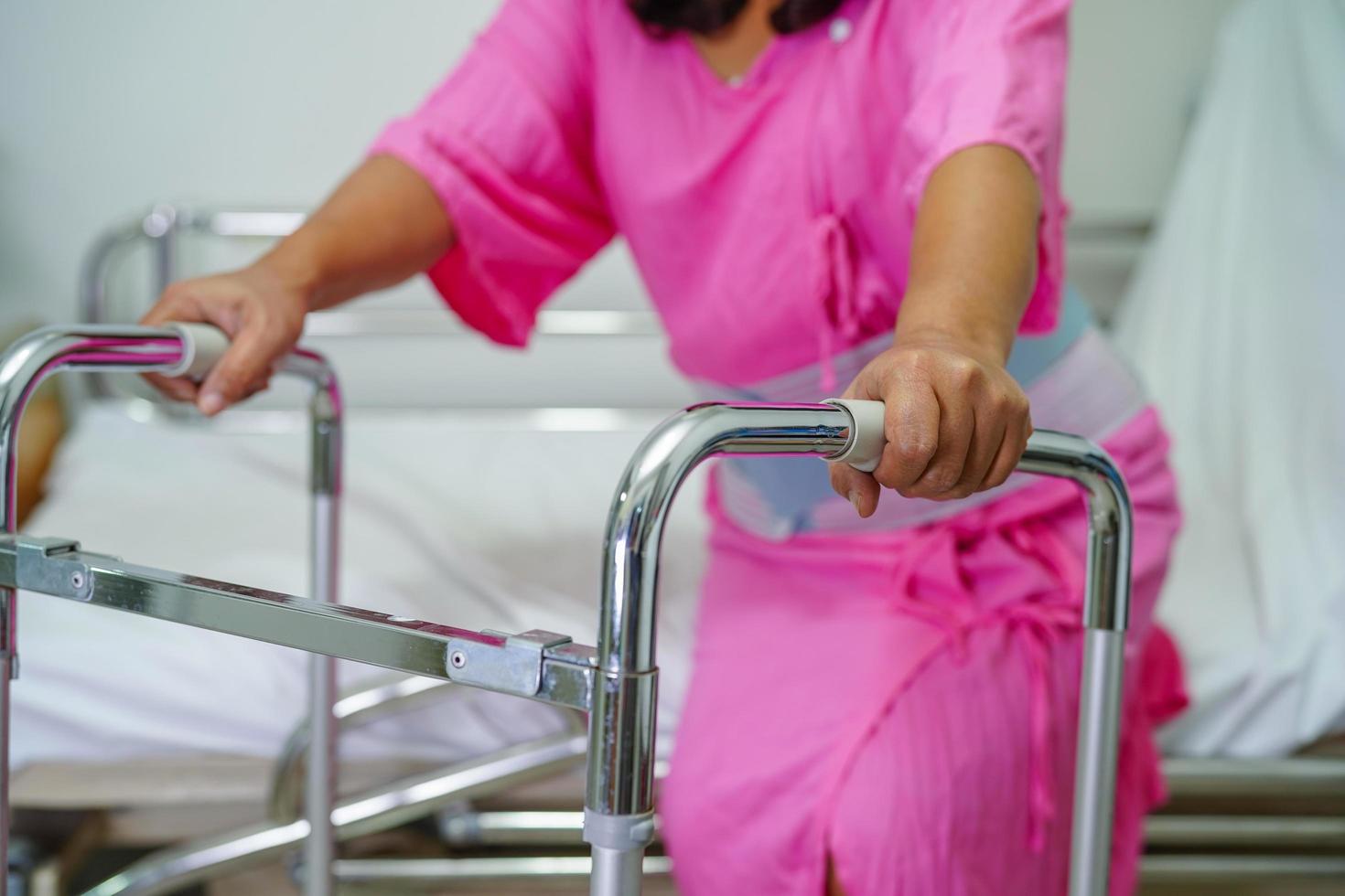 asiatisk medelålders dam kvinna patient promenad med rollator på omvårdnad sjukhusavdelning foto