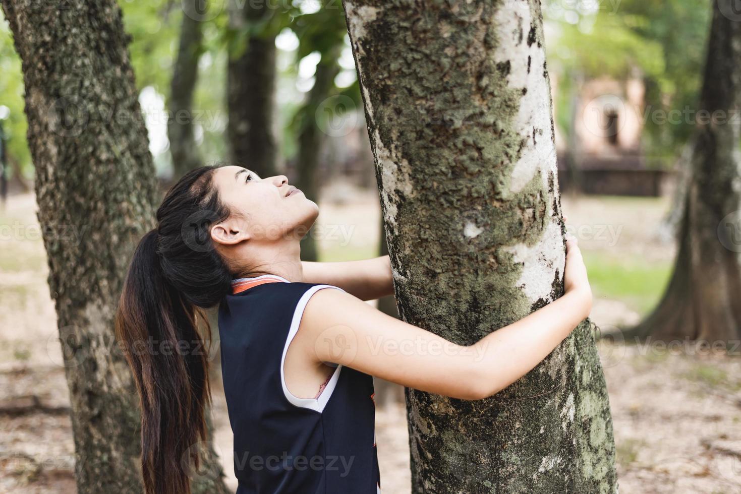 ung kvinna kramar ett stort träd, älskar natur koncept. foto