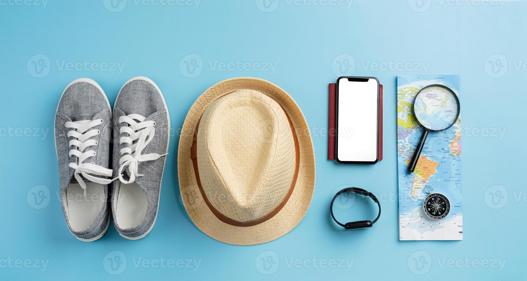 toppvy resetillbehör med skor, karta, smartphone med mockup-skärm, hatt. turistiska nödvändigheter. foto