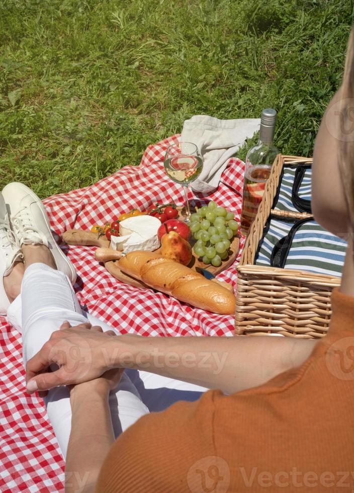 oigenkännlig ung kvinna i vita byxor utanför ha picknick, äta och spela gitarr, se bakifrån foto