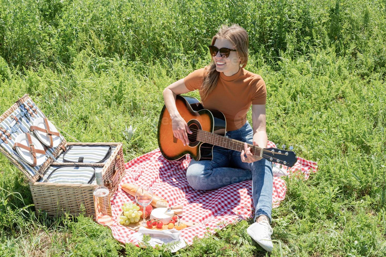 ung kvinna spelar gitarr på en picknick foto