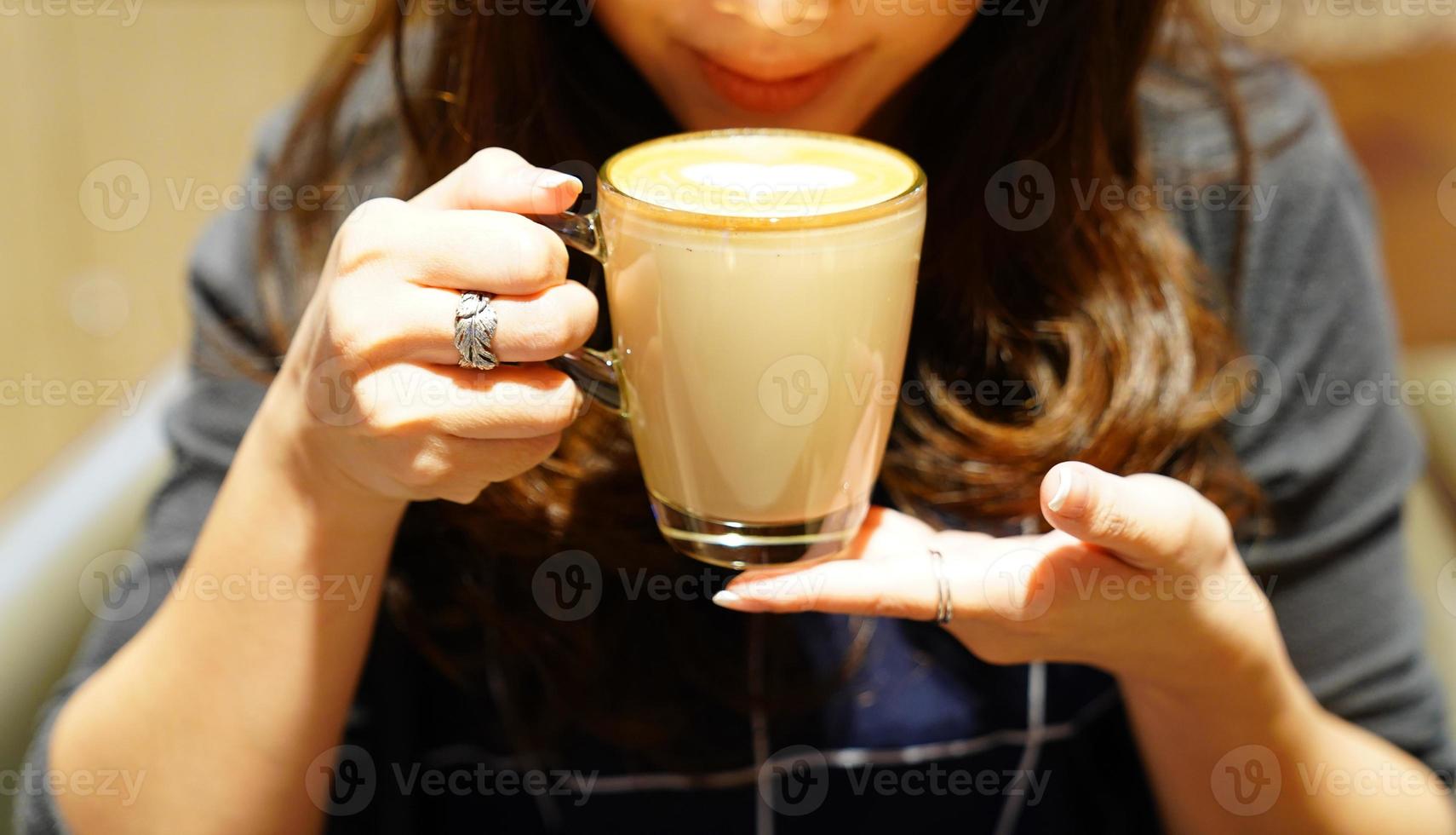 varmt latte kaffe i den asiatiska flickans hand, post och redo att drickas. foto