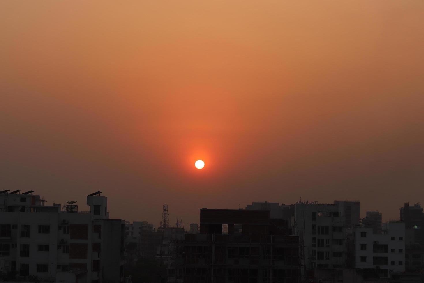 kväll solnedgång fotografering på stadsbild bakgrund. solnedgångs- eller soluppgångsfoto av ett stadsområde. vackert och varmt solnedgångslandskap skott i dhaka, bangladesh. vacker röd sol före gryningen. foto