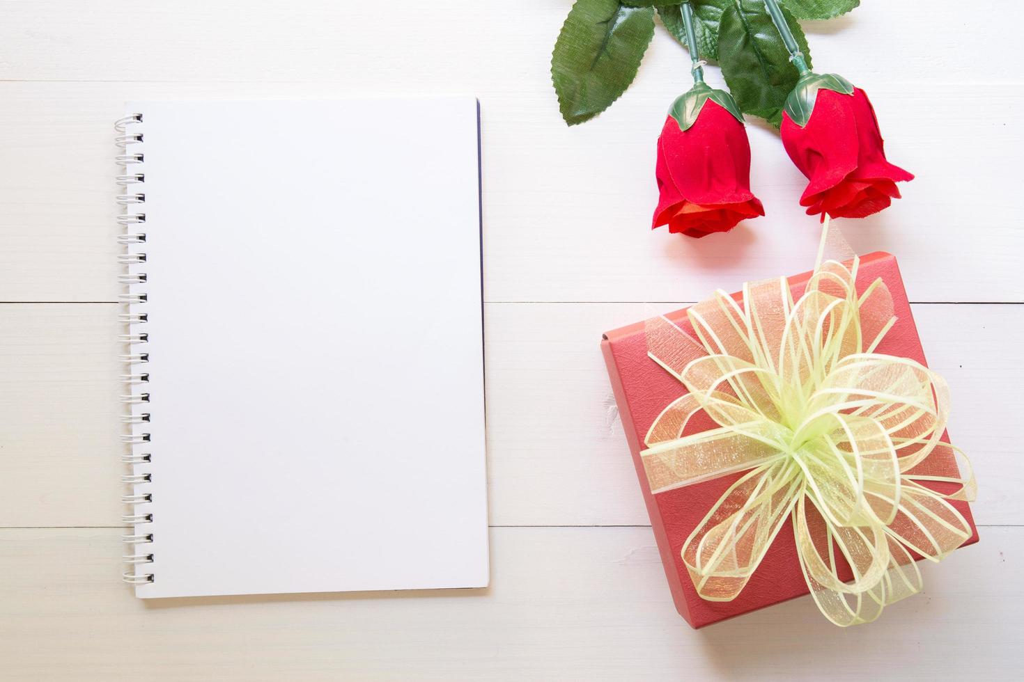 närvarande röd ros blomma och anteckningsbok och presentförpackning med kopia utrymme på träbord, 14 februari av kärleksdagen med romantiska, alla hjärtans semester koncept. foto