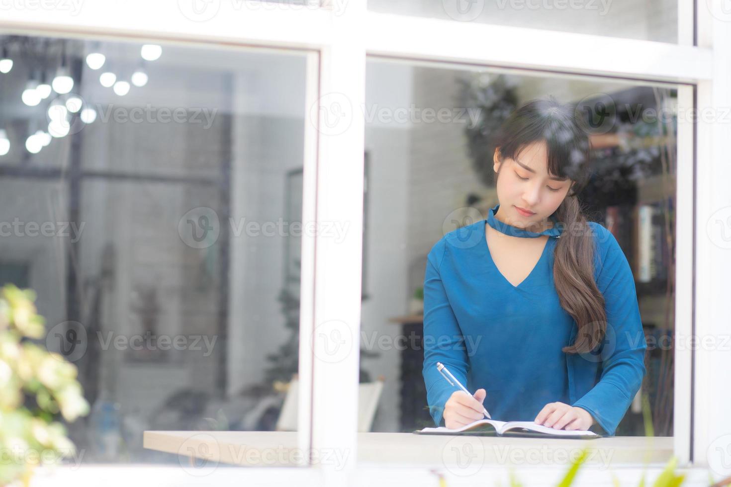 vackert porträtt ung asiatisk kvinna författare skriver på anteckningsbok eller dagbok med glad, livsstil av asiatisk flicka är student, kvinnlig planering arbete, utbildning och affärsidé. foto