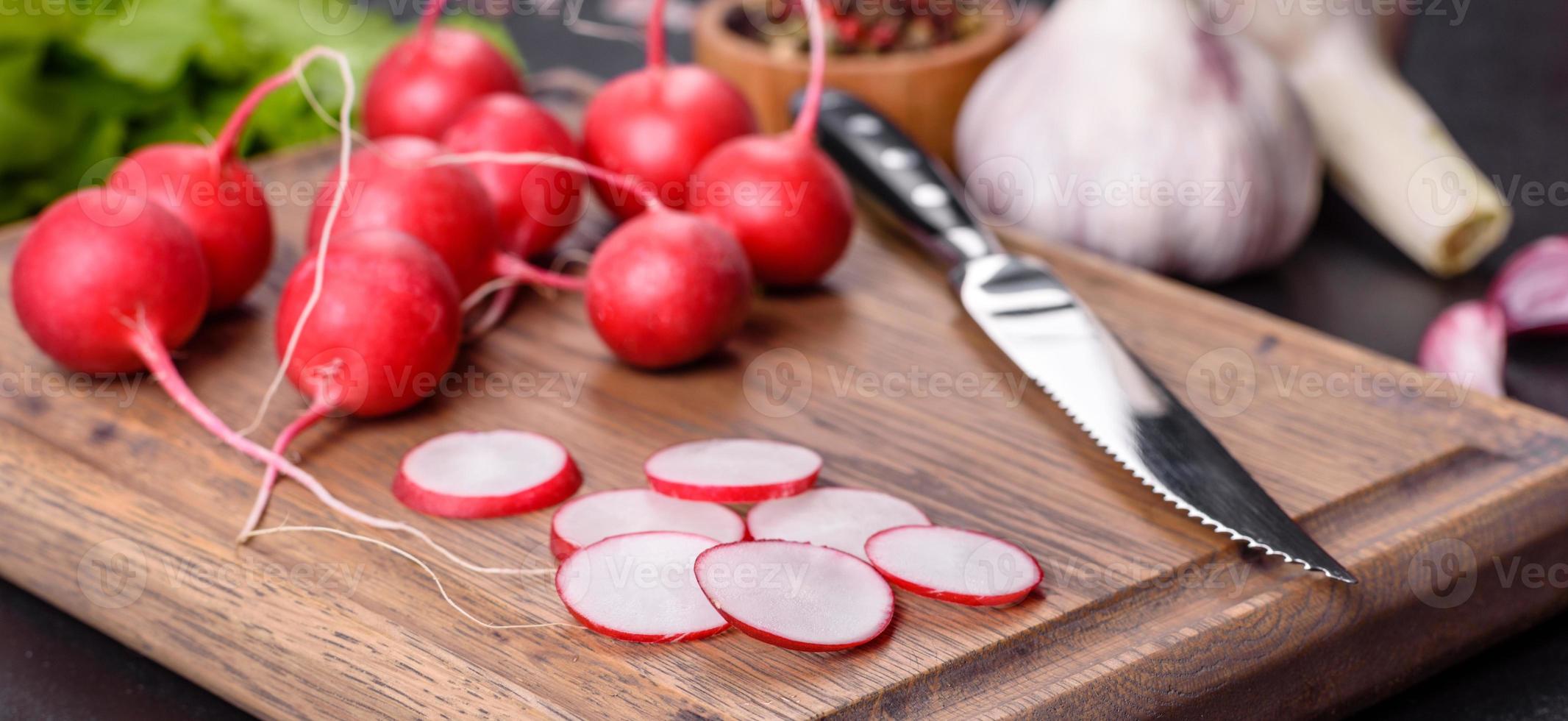 läcker färsk röd rädisa som ingrediens för att göra vårsallad på träskärbräda foto