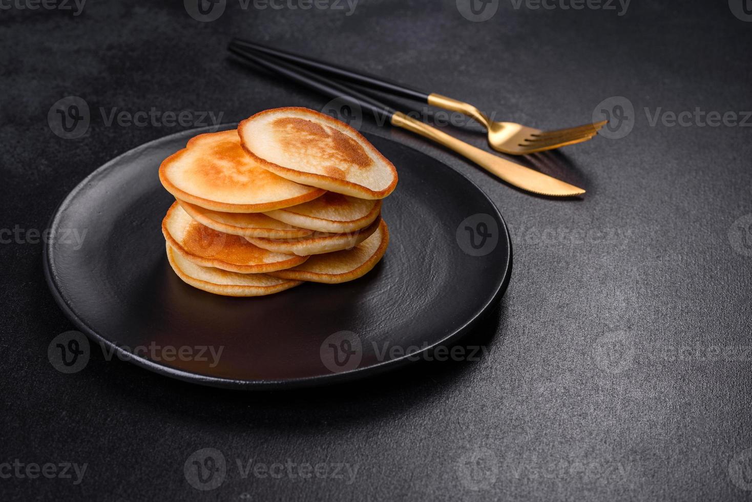 läckra färska pannkakor på en svart tallrik mot en mörk betongbakgrund foto