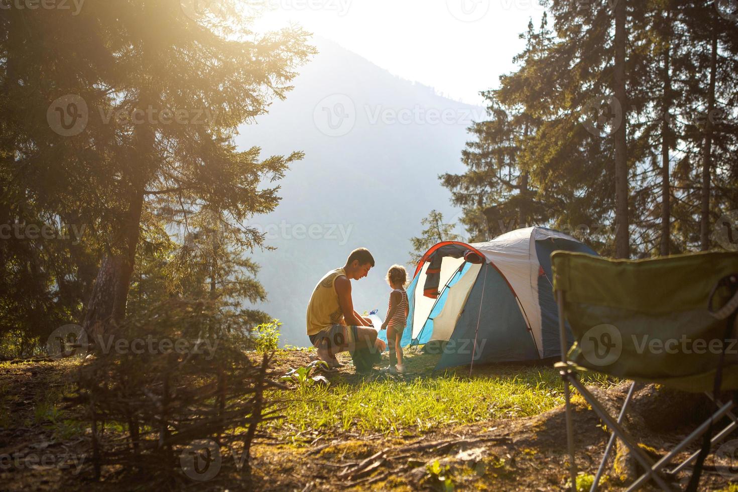 pappa och dotter på 2 år nära ett tält på en camping i skogen i bergen.familjens friluftsliv, miljövänliga äventyr, överlevnad i det vilda. foto