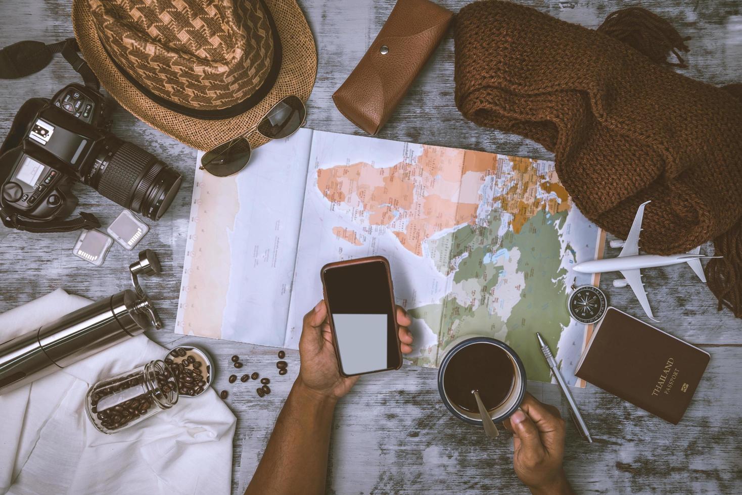 turistplaneringssemester med hjälp av världskarta och kompass tillsammans och kaffekopp med kaffekvarn med andra resetillbehör. förbereder för resan. reseplanering koncept semester med karta foto