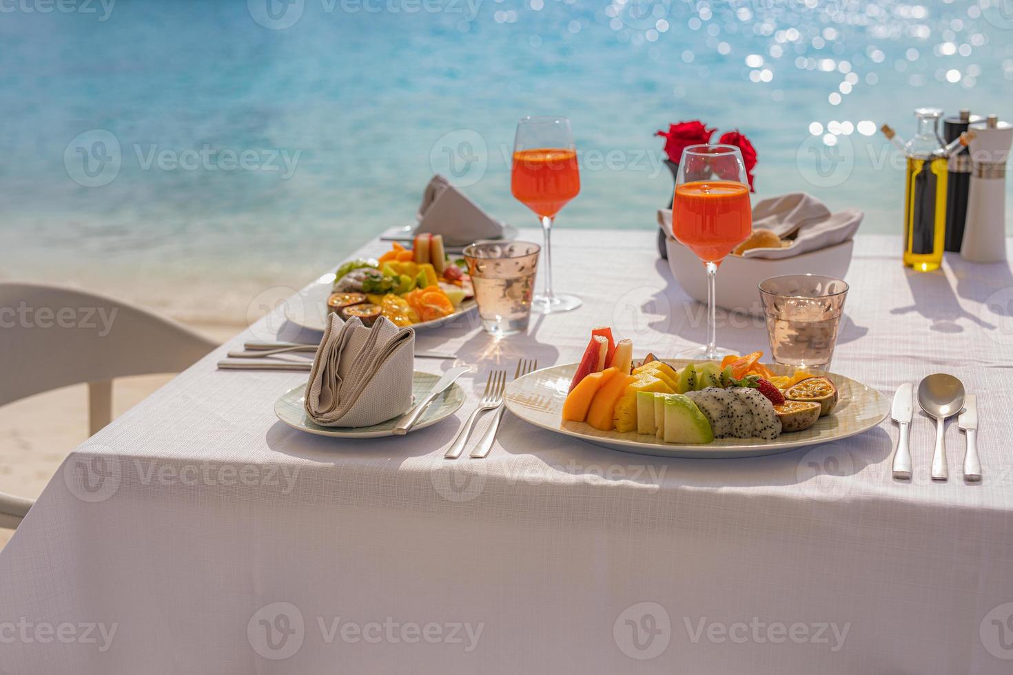 lyxig frukostmat på vitt bord, med vacker tropisk havsutsiktbakgrund, morgontids sommarlov och romantiskt semesterkoncept, lyxresor och livsstil foto