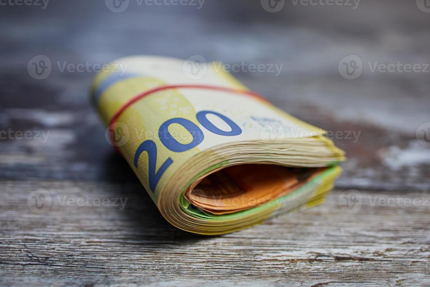 makro färgfoto av tvåhundra eurosedlar mot träyta, bundna med ett hushållsgummi foto