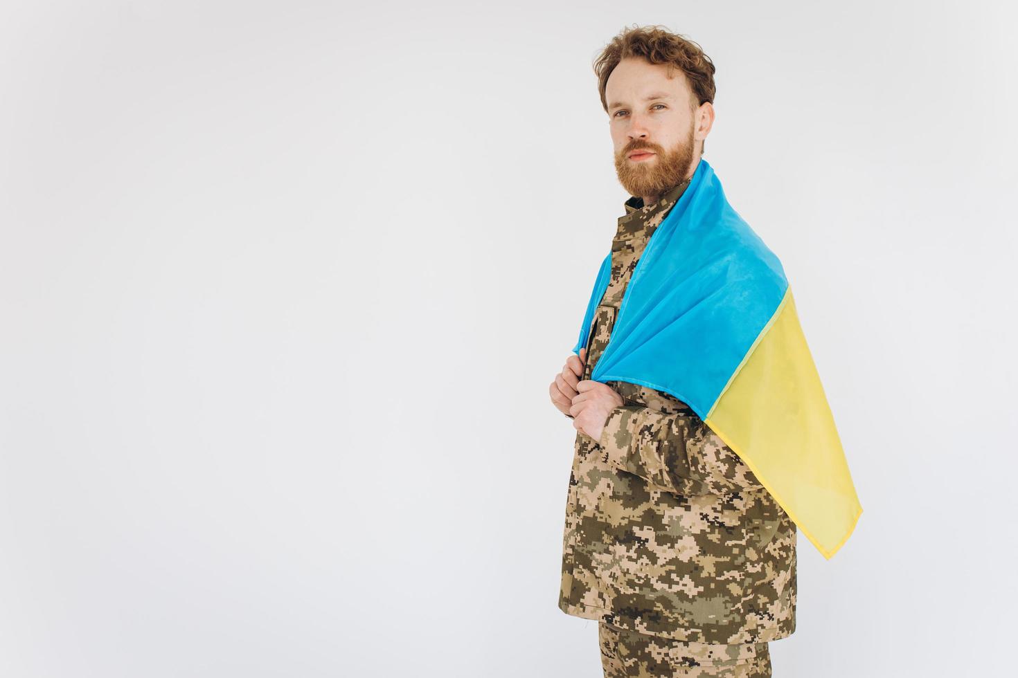 ukrainsk patriotsoldat i militäruniform med en gul och blå flagga på en vit bakgrund foto