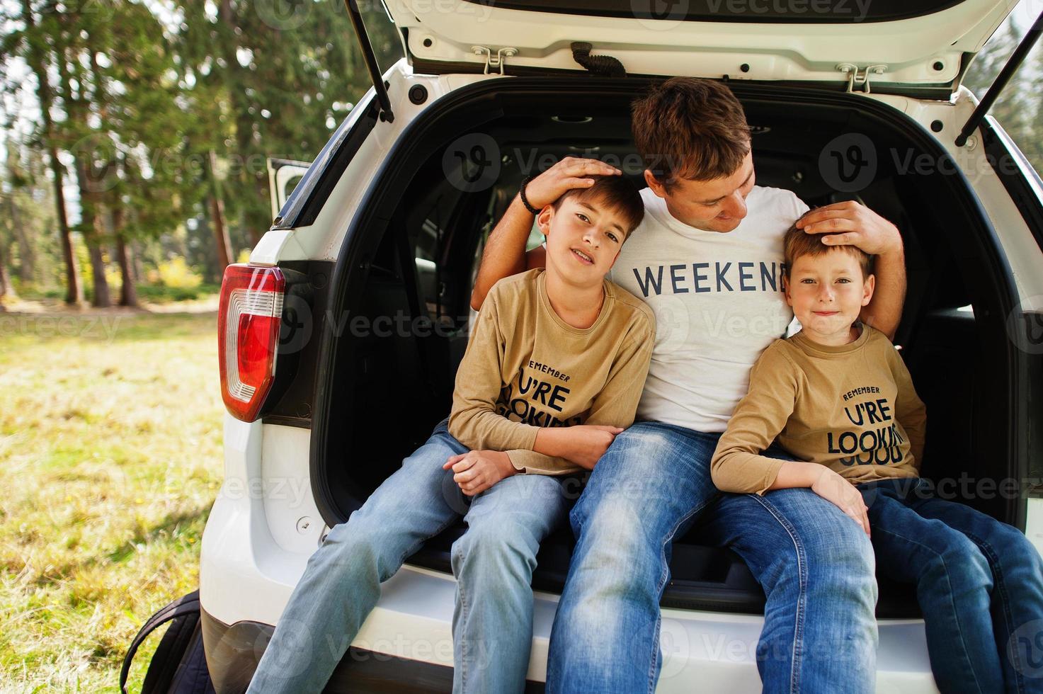 familj vid fordonsinredning. far med sina söner. barn i bagageutrymmet. reser med bil i bergen, atmosfär koncept. foto