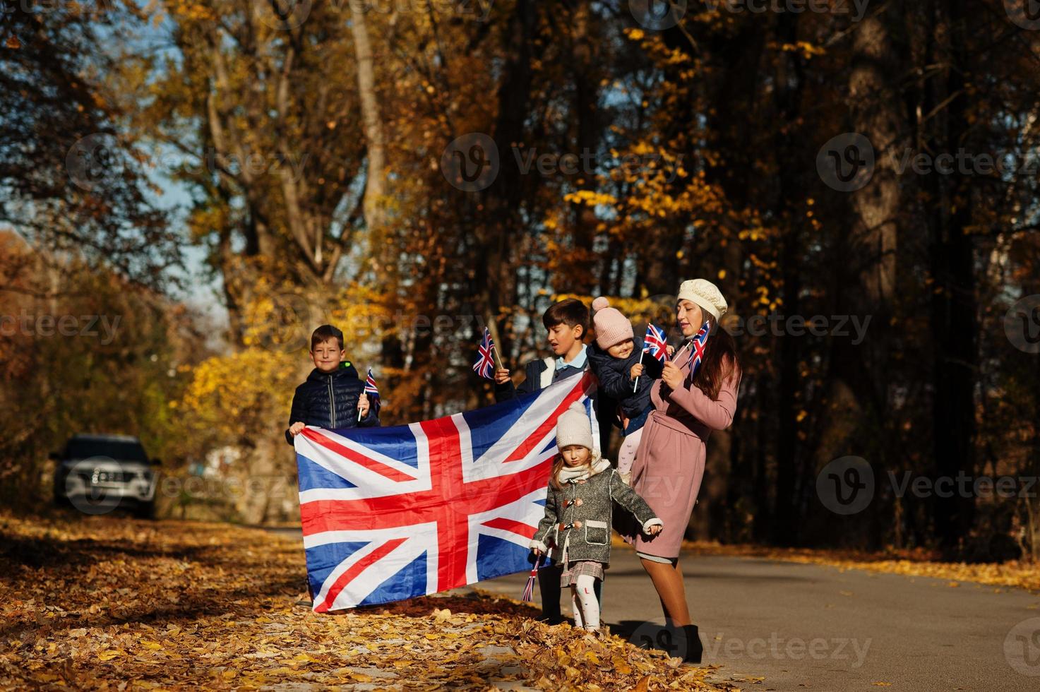 Storbritanniens nationaldag. familj med brittiska flaggor i höst park. brittiskhet firar Storbritannien. mamma med fyra barn. foto