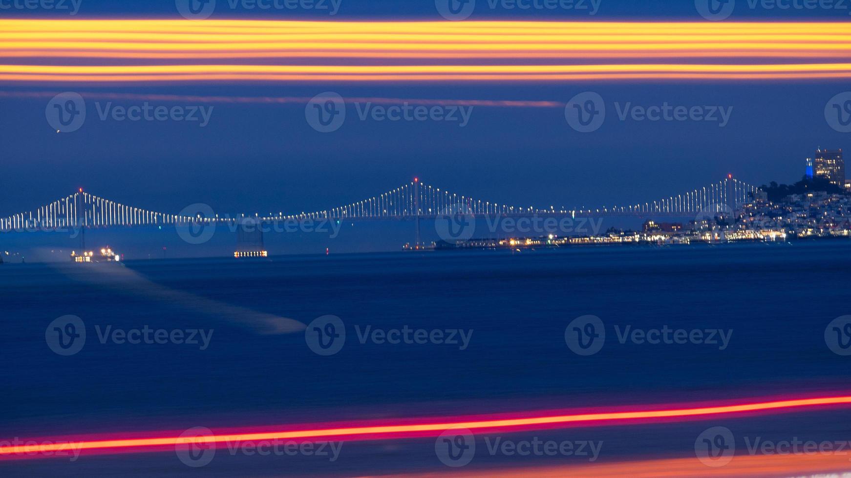 Bay bridge i fjärran med lång exponering trafikljus i förgrunden foto