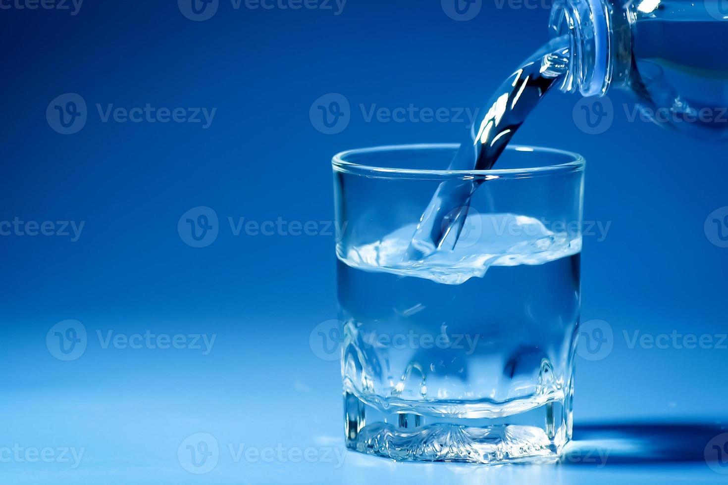 studio skott rent dricksvatten hälls i glas och naturlig blå bakgrund. hälsosamt dricksvatten koncept foto