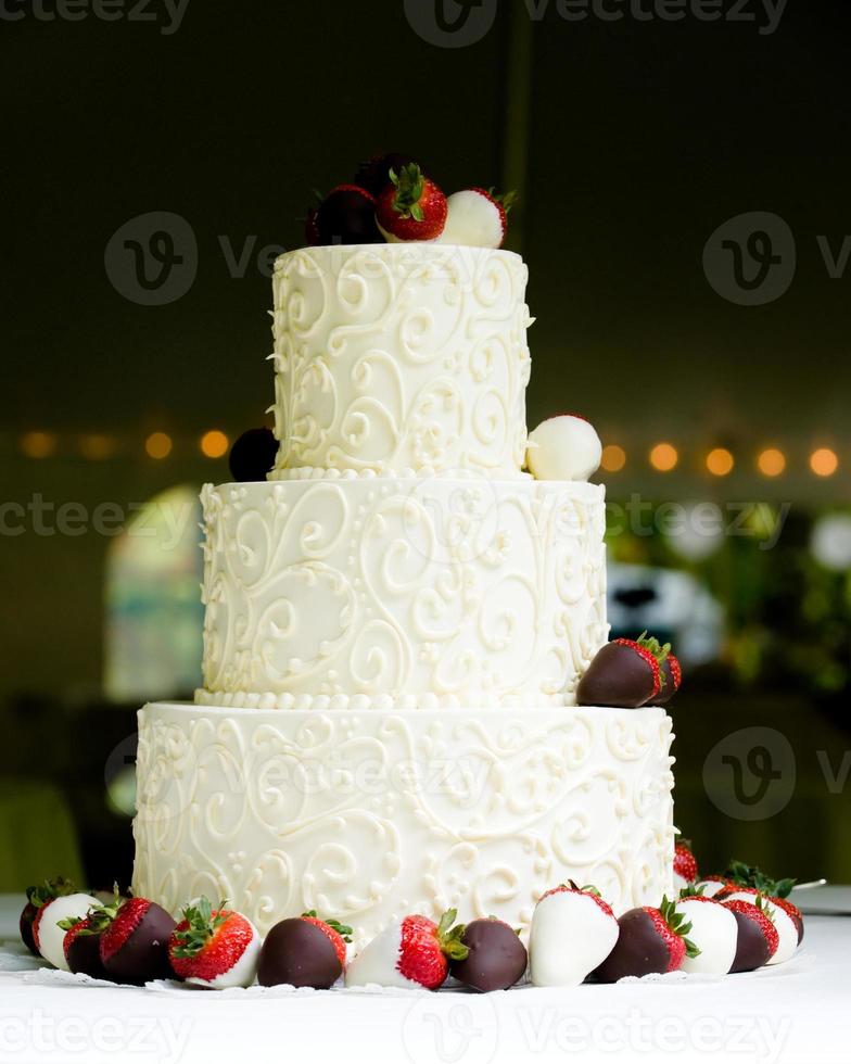 tre lager bröllopstårta med choklad täckta jordgubbar foto