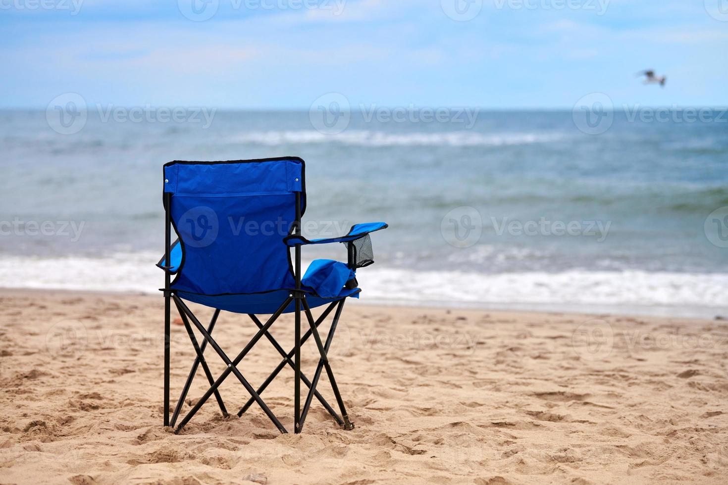 blå fällstol på havsstranden, utan människor, ensam strandsemester, ensamhet foto