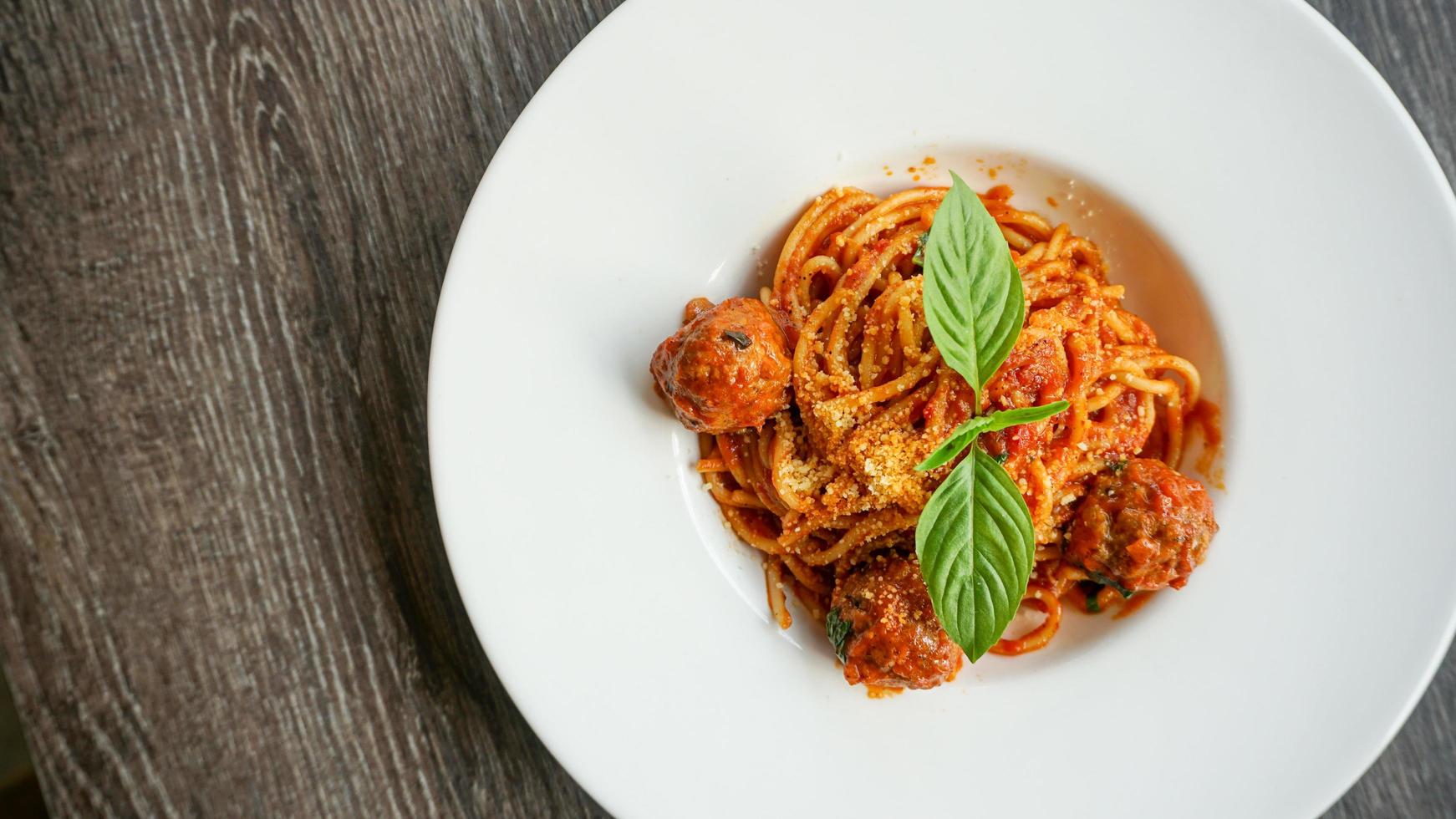 ovanifrån utsikt spaghetti köttbullar med tomatsås i vit platta på träbord foto