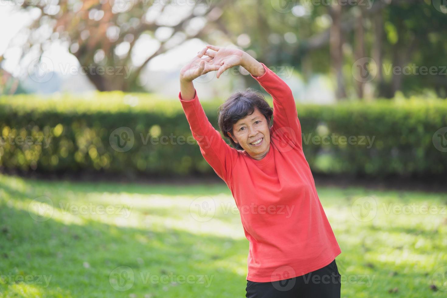 senior asiatisk kvinna kroppsuppvärmning innan träning. gammal kvinna stretching innan jogging i trädgården, sport idrottare kör koncept. foto