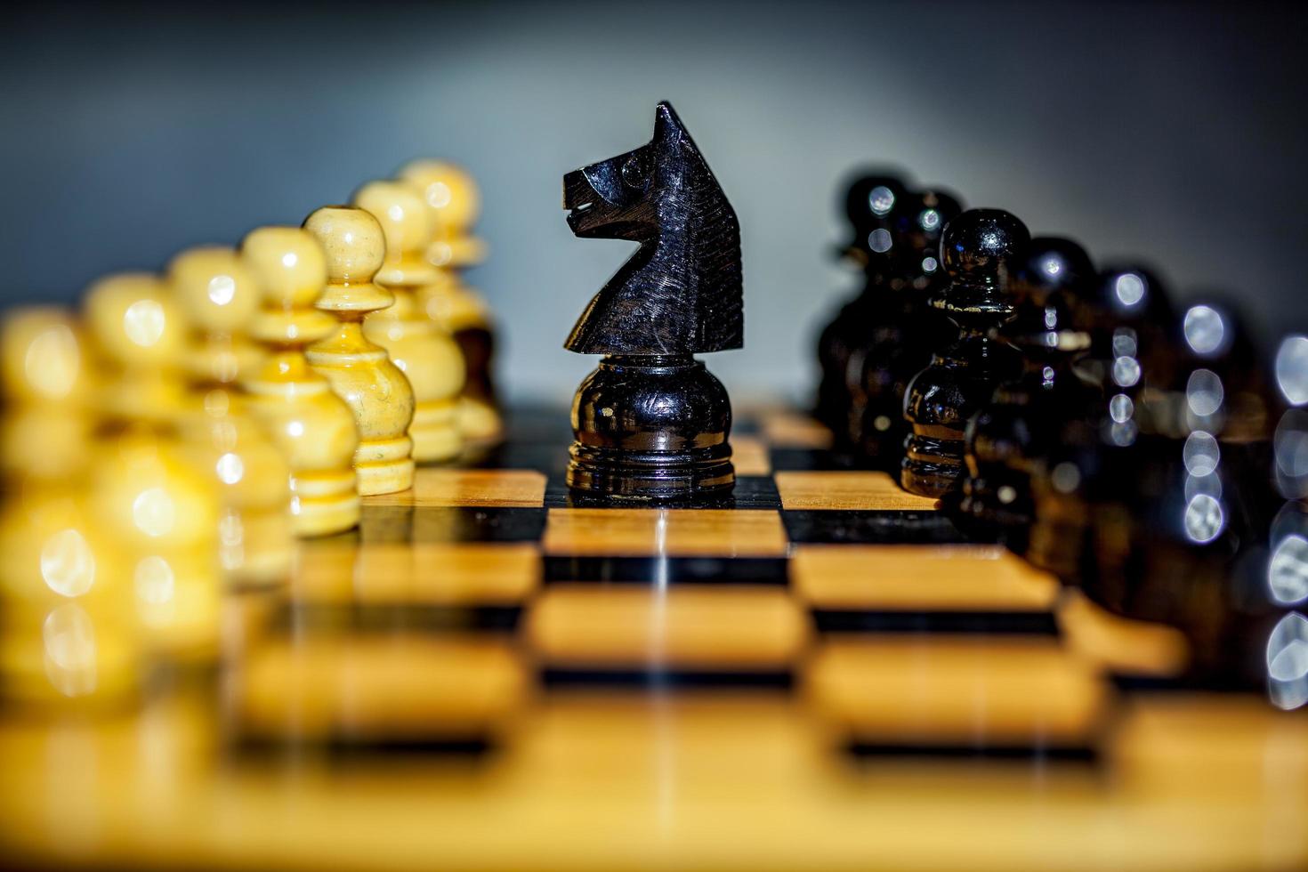 närbild av en svart riddare och bönder på ett schackbräde foto