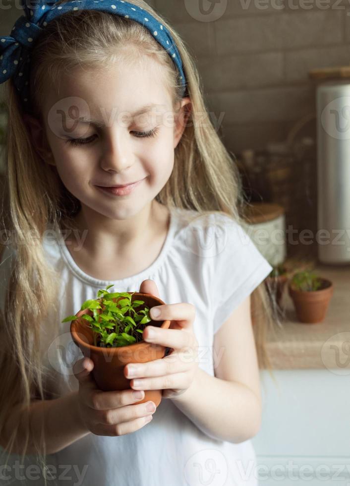 liten flicka som håller en kruka med plantor foto