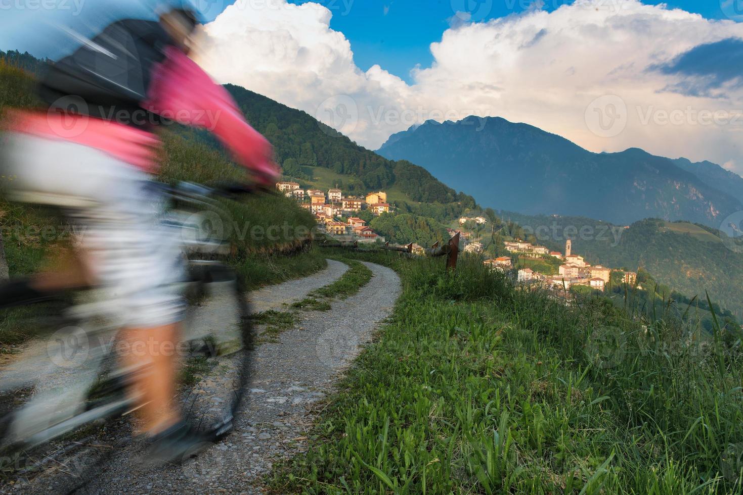 oskärpa effekt av en mountainbike på en grusväg mot den lilla bergsbyn foto