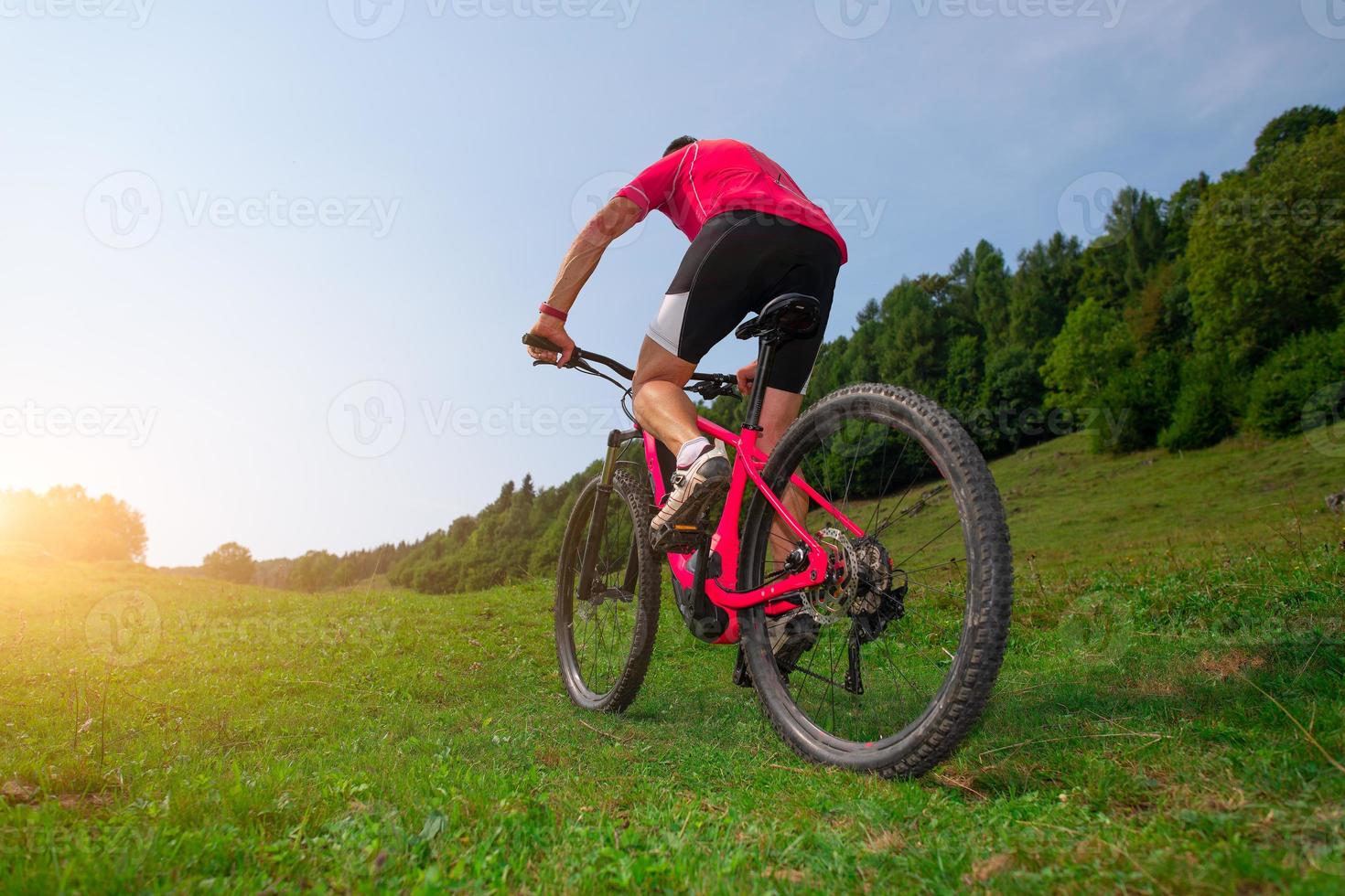 cyklist man klättrar på en äng med mountainbike foto
